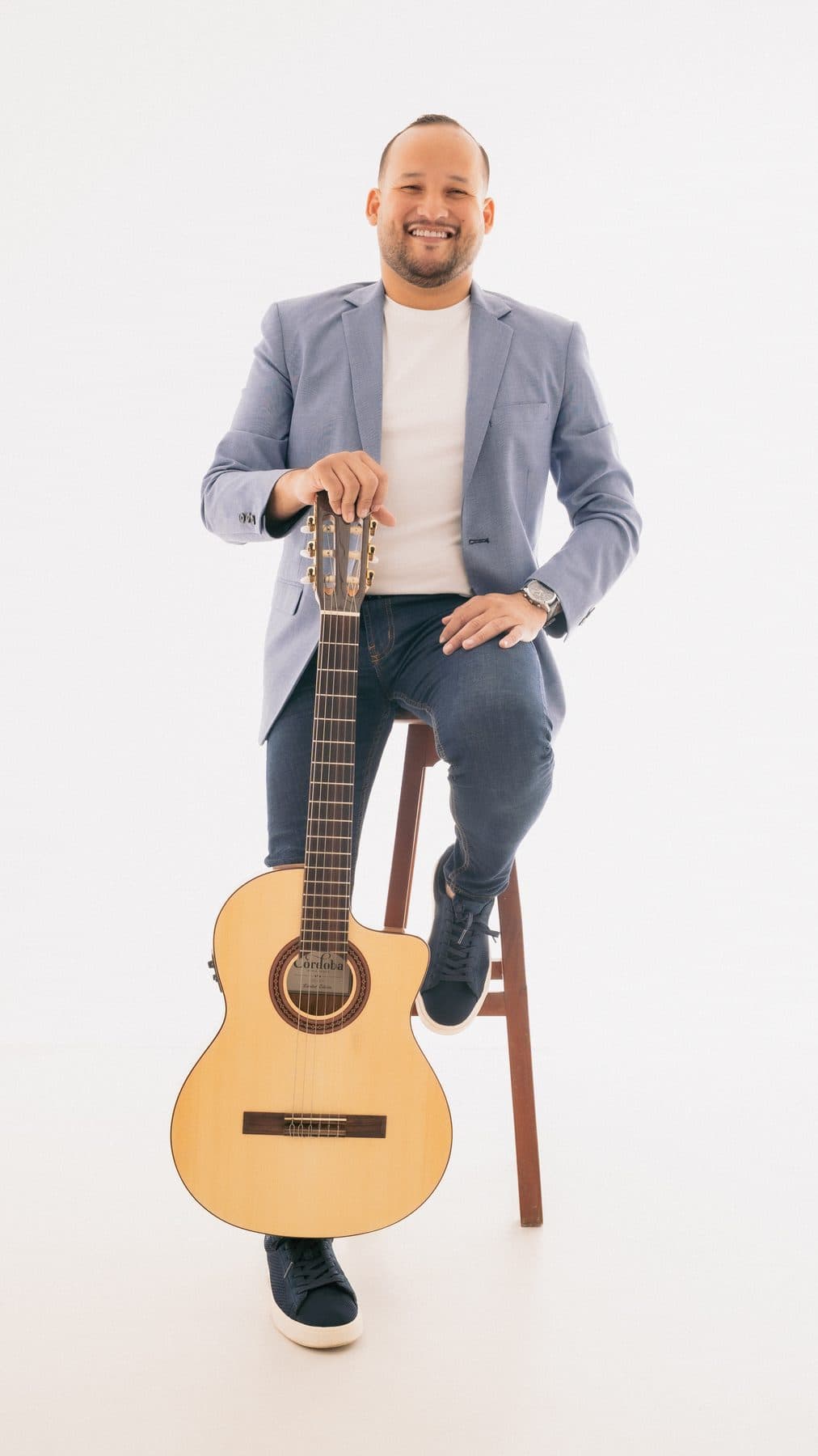 Juan Cañas sentado con su guitarra en sesión de estudio
