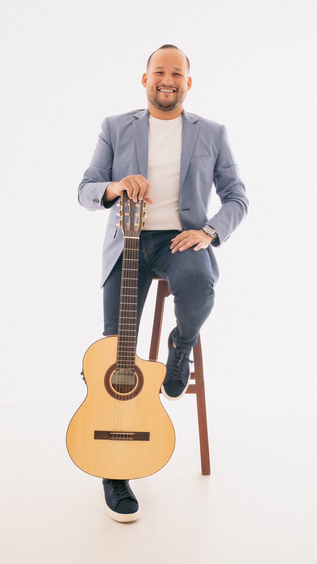 Juan Cañas sentado con su guitarra en sesión de estudio